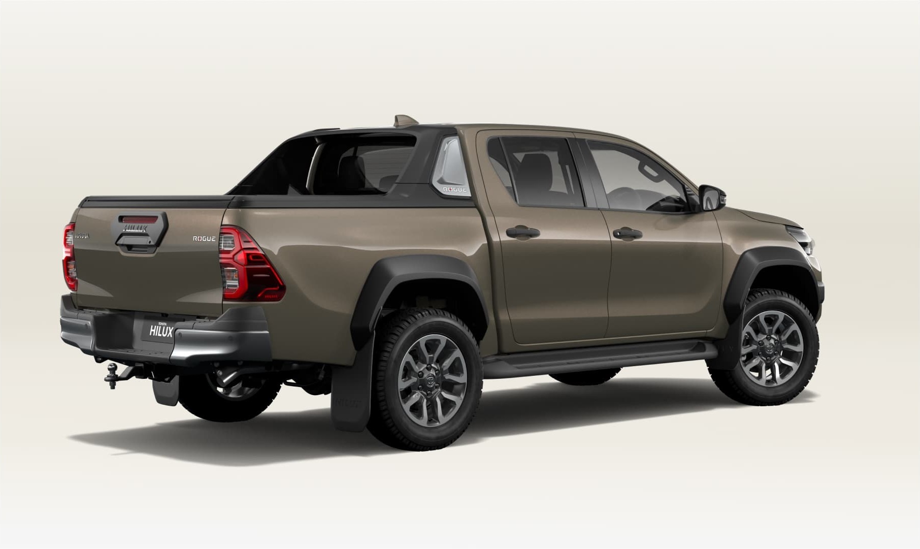 Rear three-quarter studio view of a bronze Toyota Hilux Rogue dual-cab fitted with an EGR roll cover and sports bar