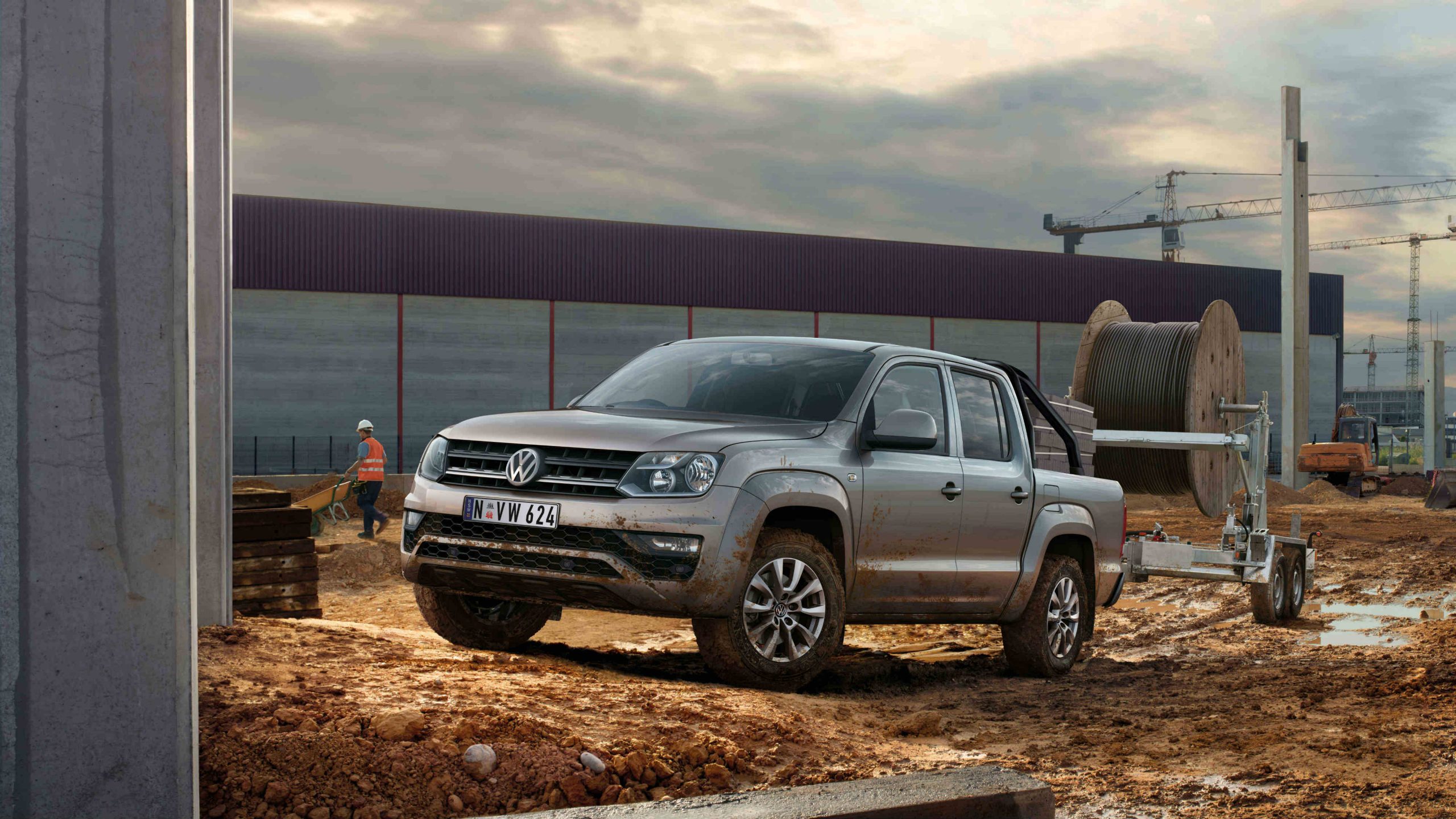 First-generation Volkswagen Amarok dual-cab with a trailer hitched, parked on a construction site