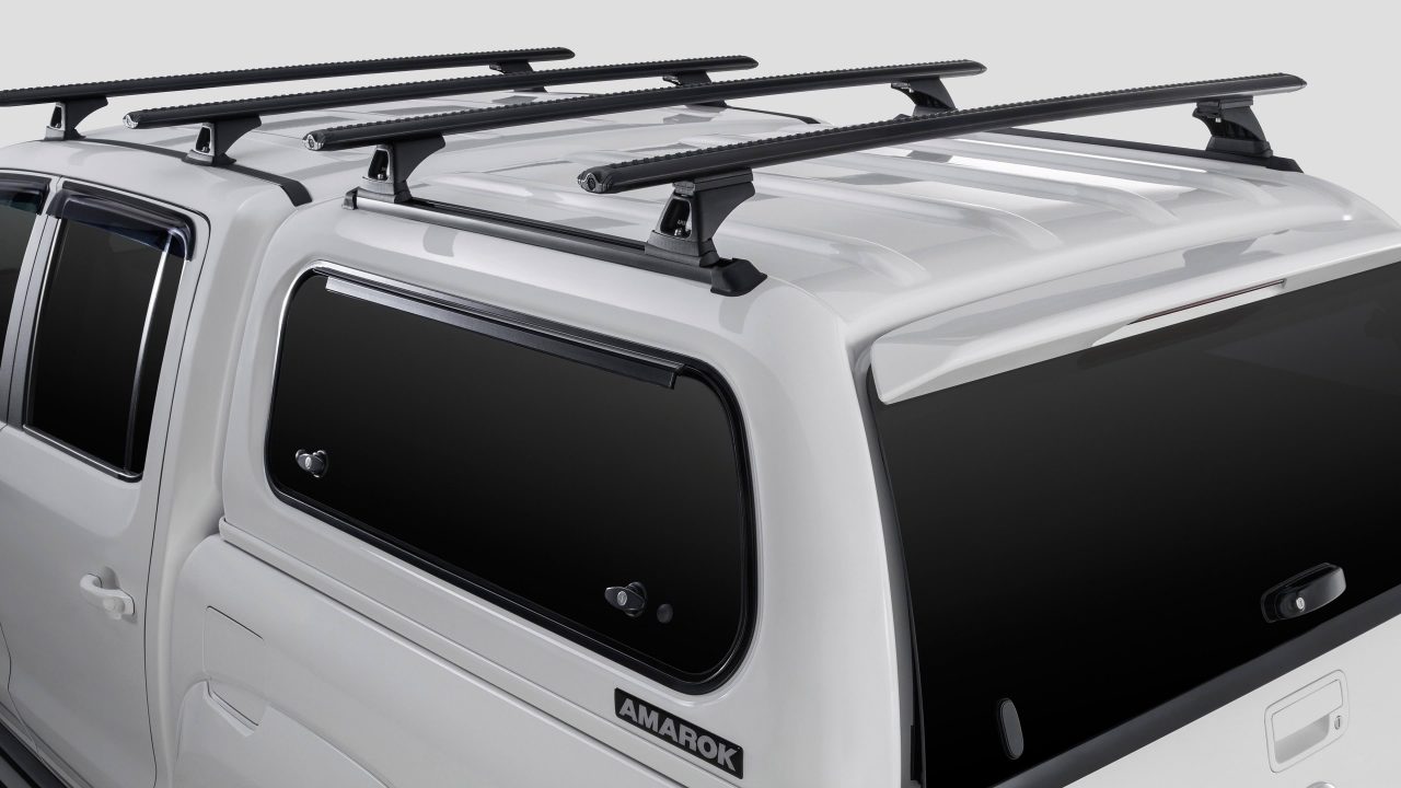 Close detail of a white Volkswagen Amarok fitted with a hard canopy, lift-up side window and four roof rack bars